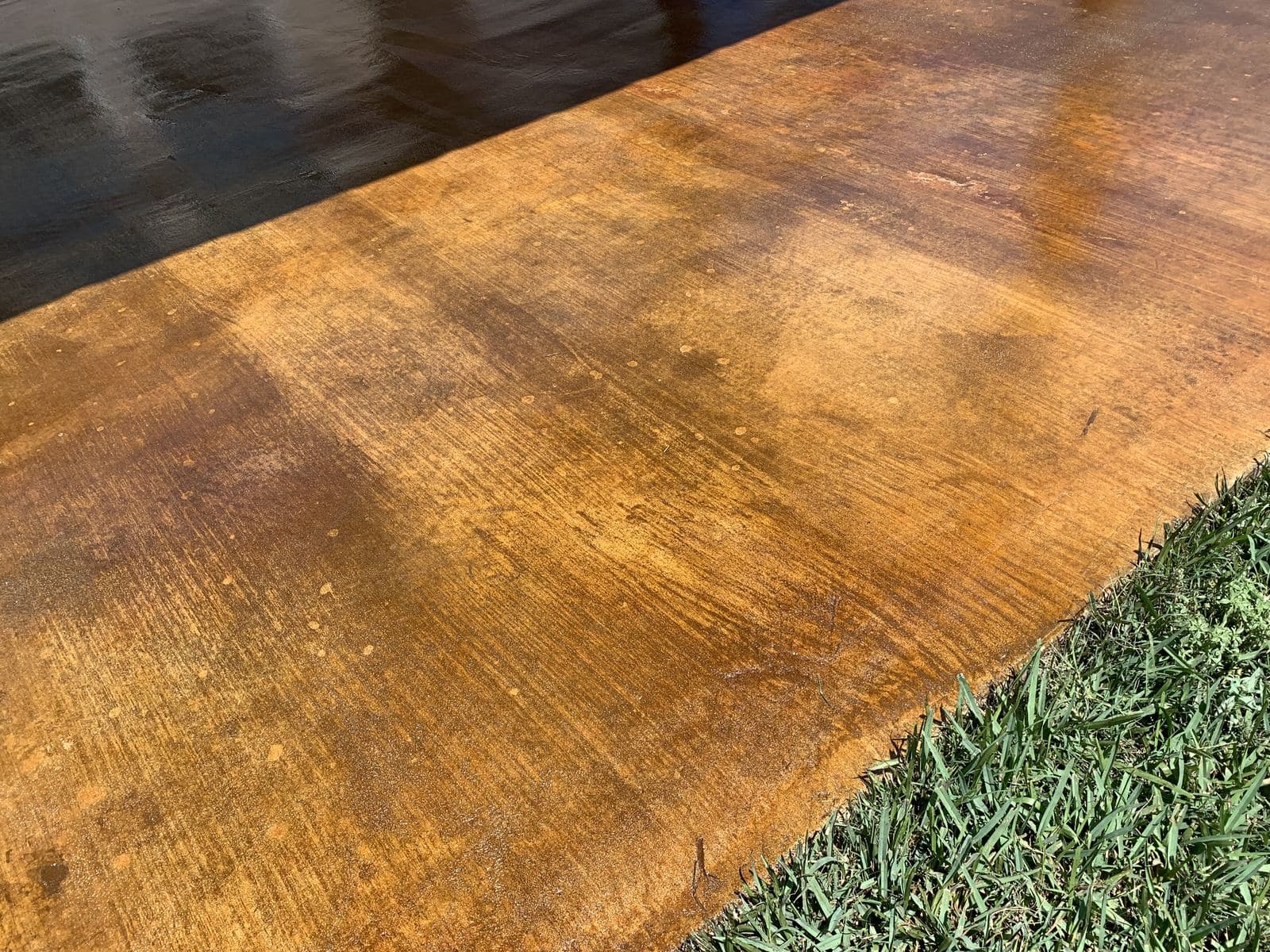 Close-up of a sealed amber acid-stained slab edge meeting the grass