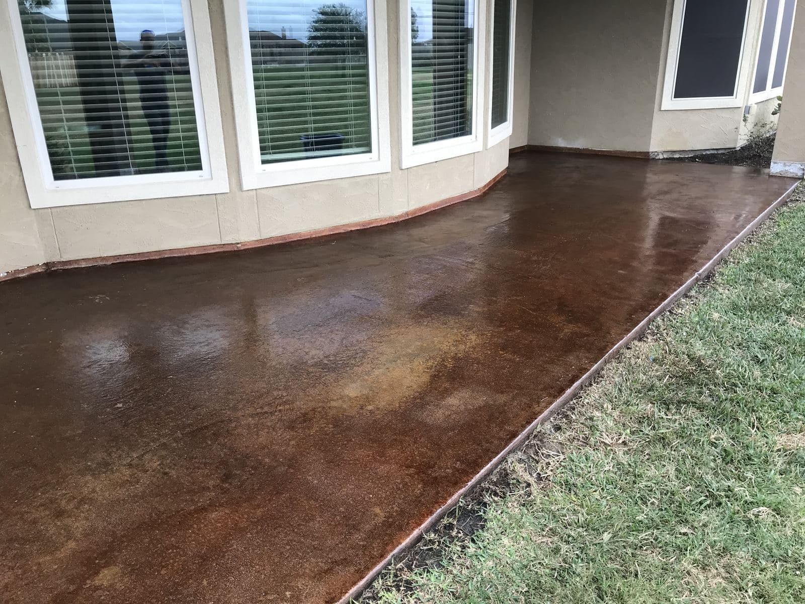 Acid-stained patio with a deep brown gloss along a row of bay windows