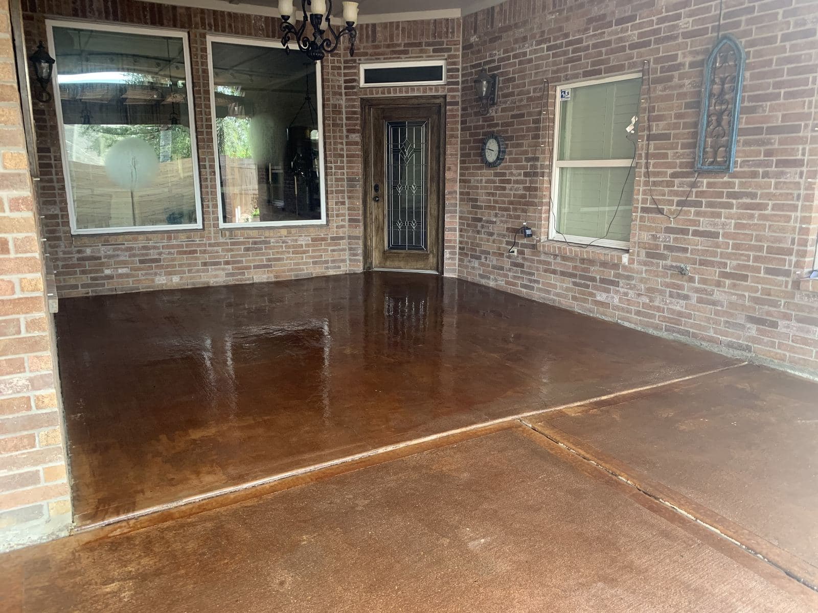 Glossy acid-stained covered patio against a brick wall and windows