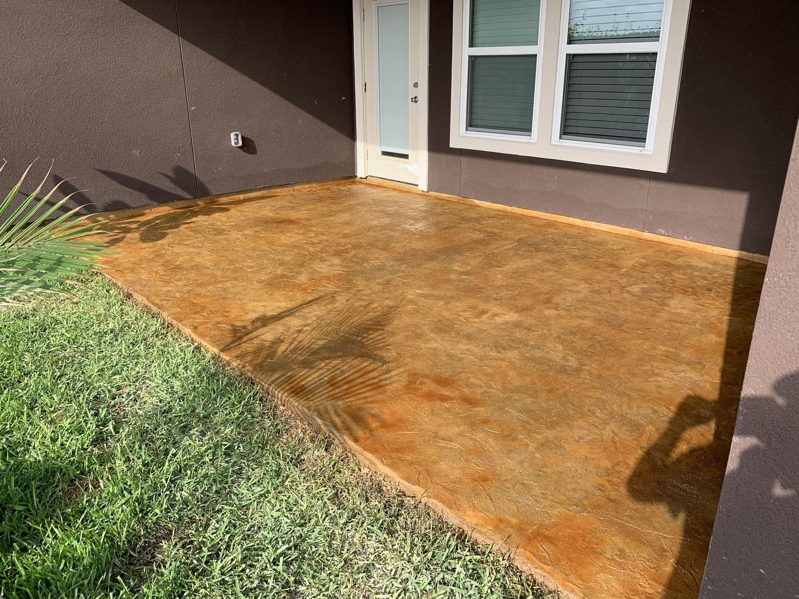 Amber acid-stained front porch slab by a home's entry door