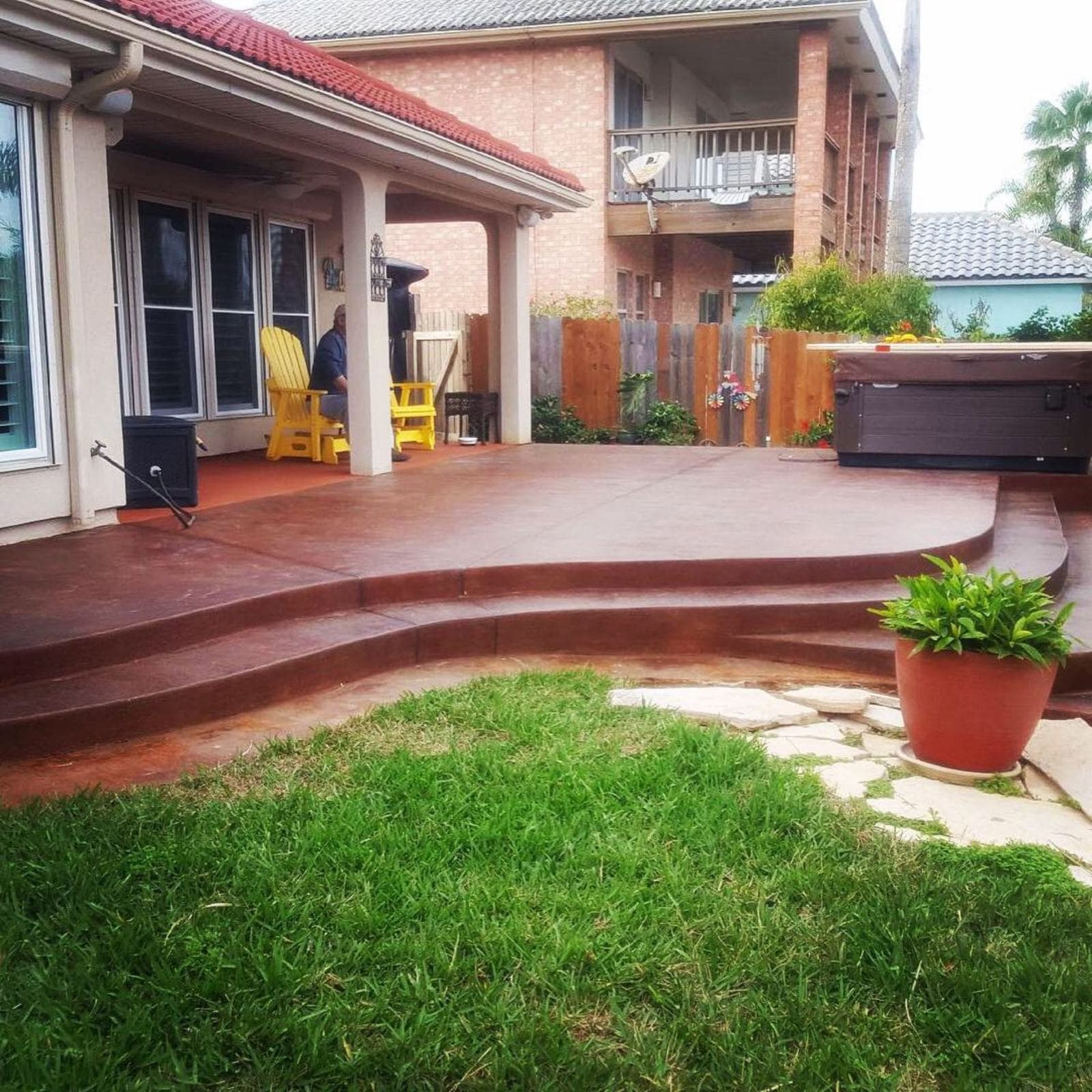 Rich mahogany acid-stained back patio with wide steps down to the lawn