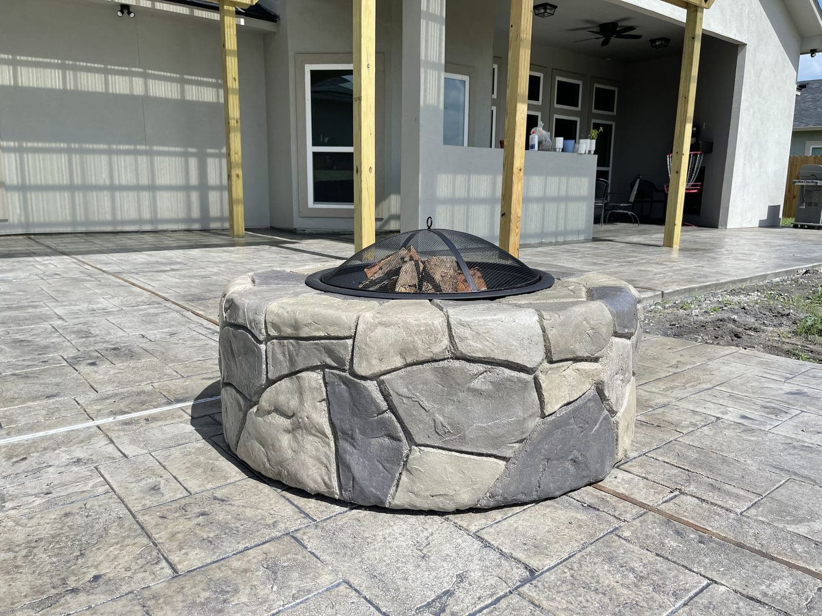 Stone-look fire pit on a gray stamped concrete patio