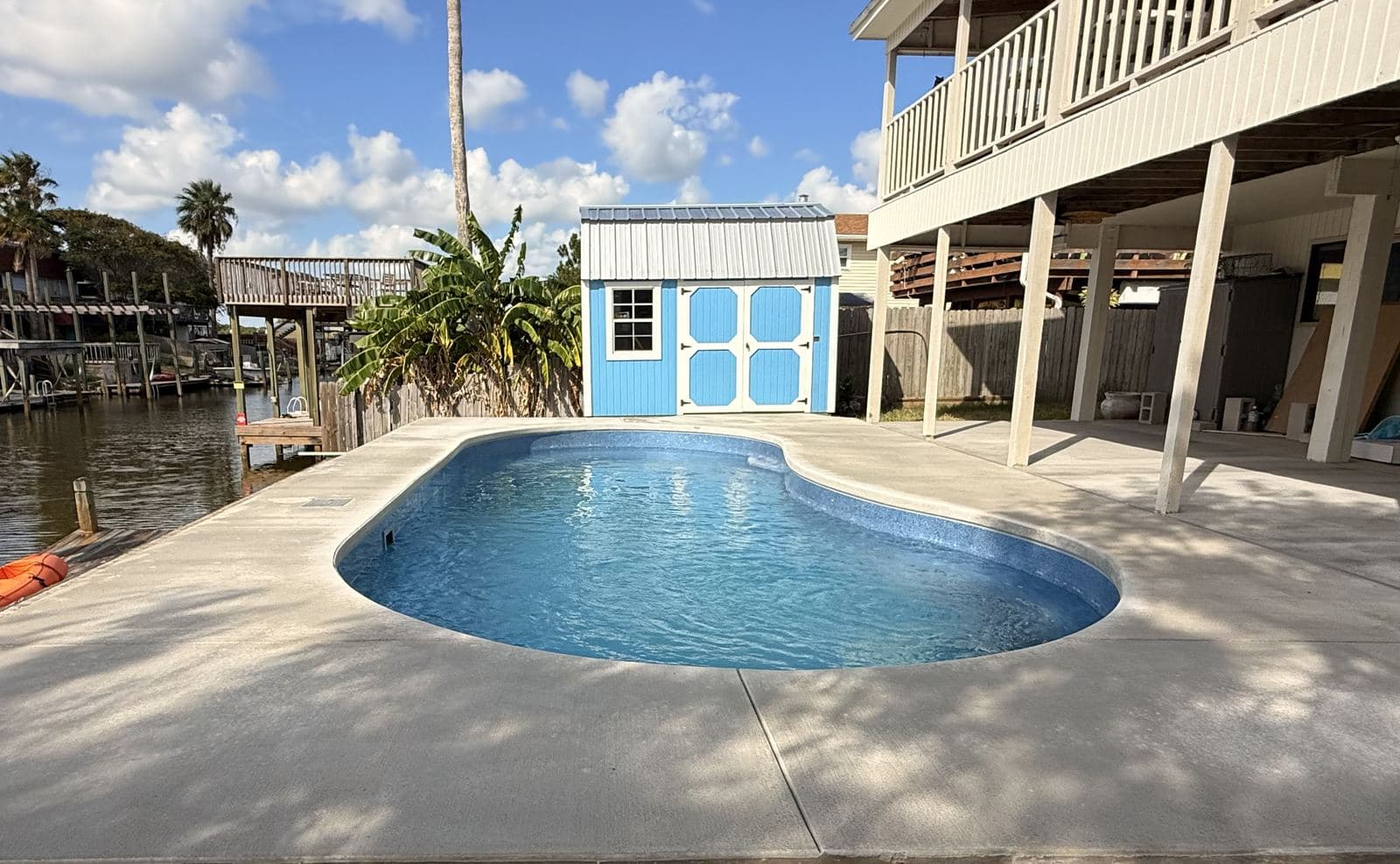 Fiberglass pool and concrete deck at a canal-front home