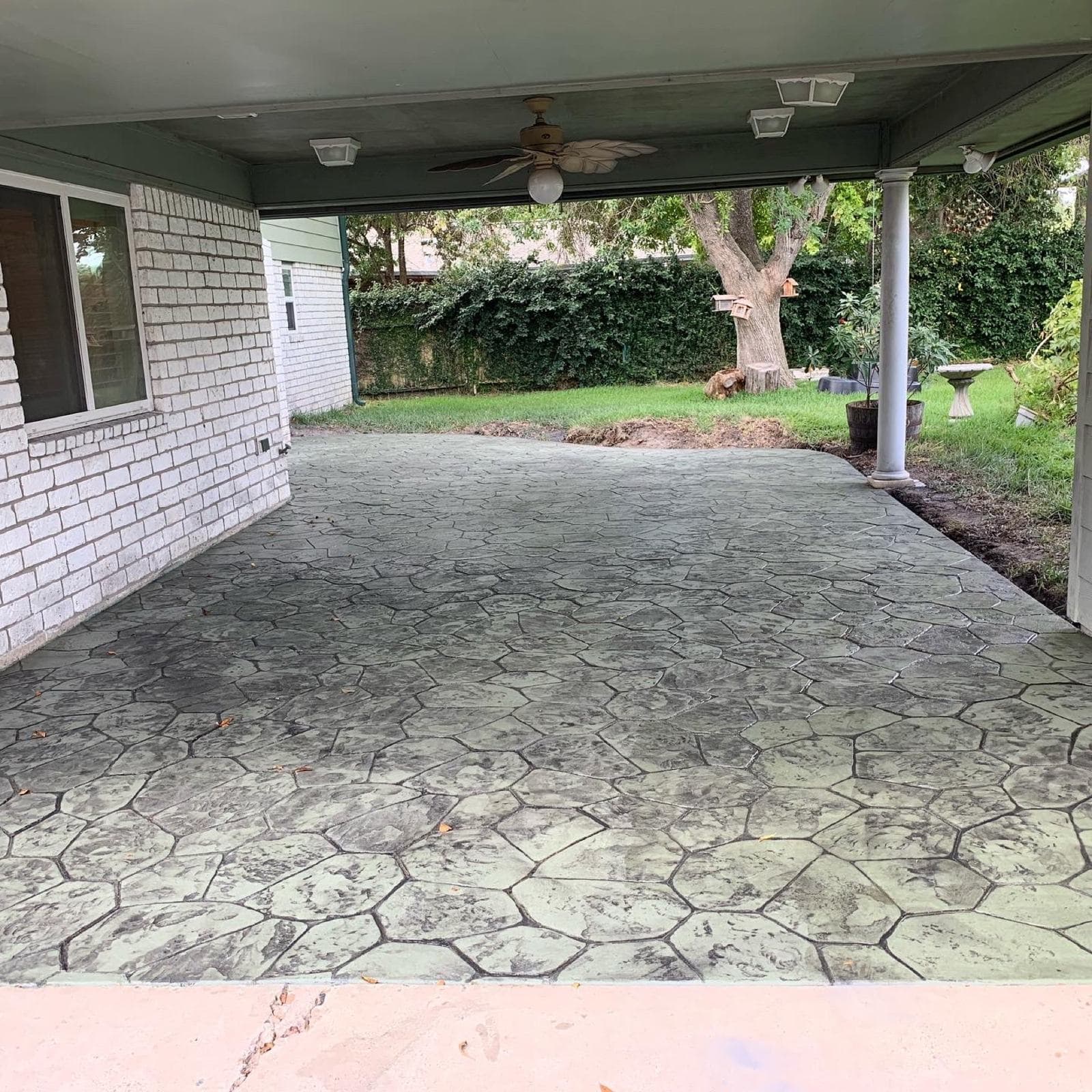 Covered patio resurfaced with a stamped concrete overlay in a flagstone pattern
