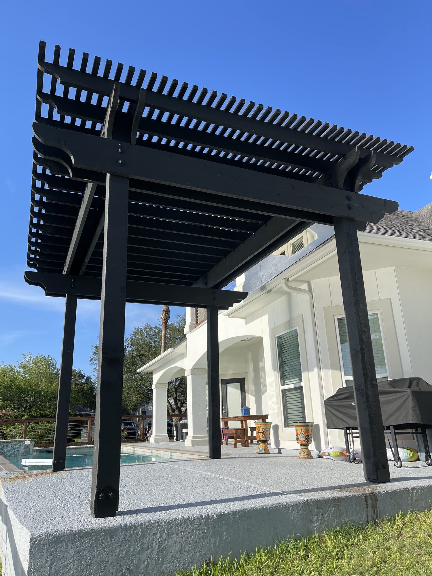 Black modern pergola beside a backyard pool
