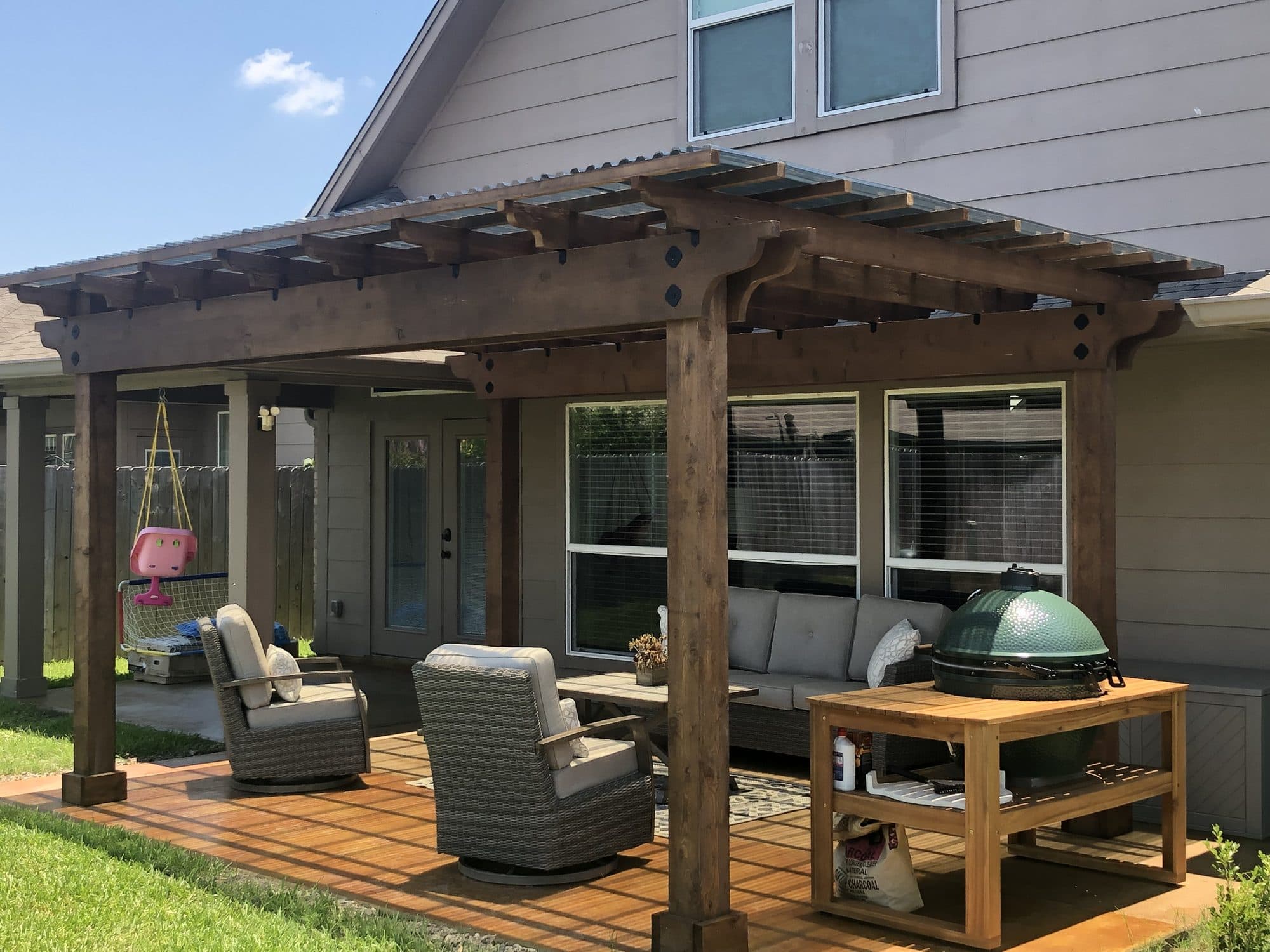 Cedar pergola over a wood-look deck with wicker seating and a kamado grill