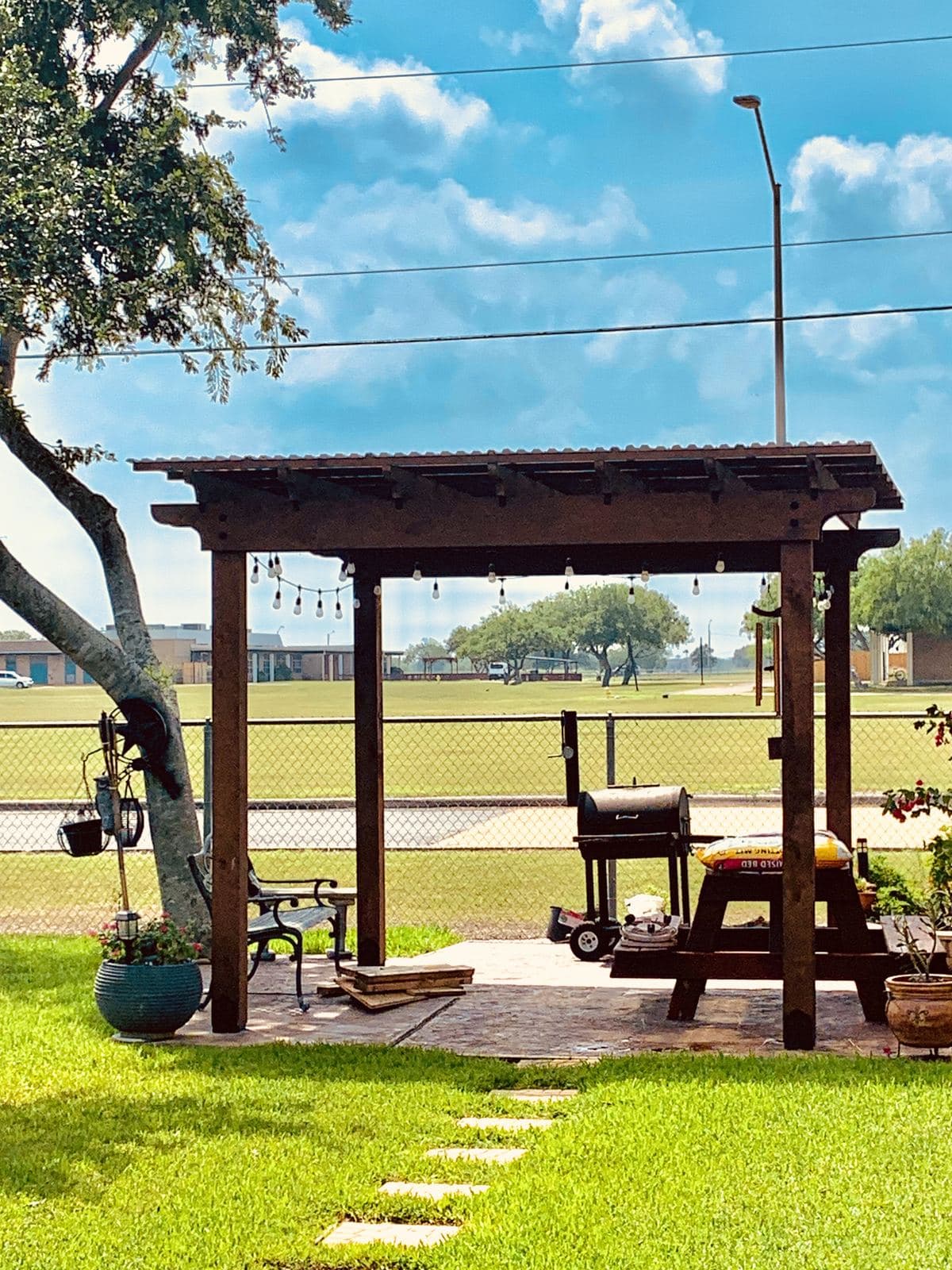 Cedar pergola over a picnic table and smoker in a back yard