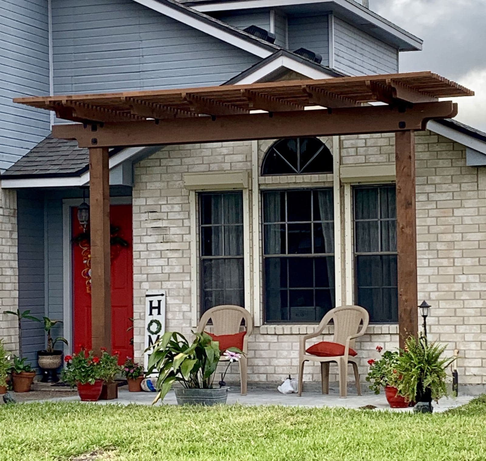 Cedar pergola over the front porch of a two-story brick home