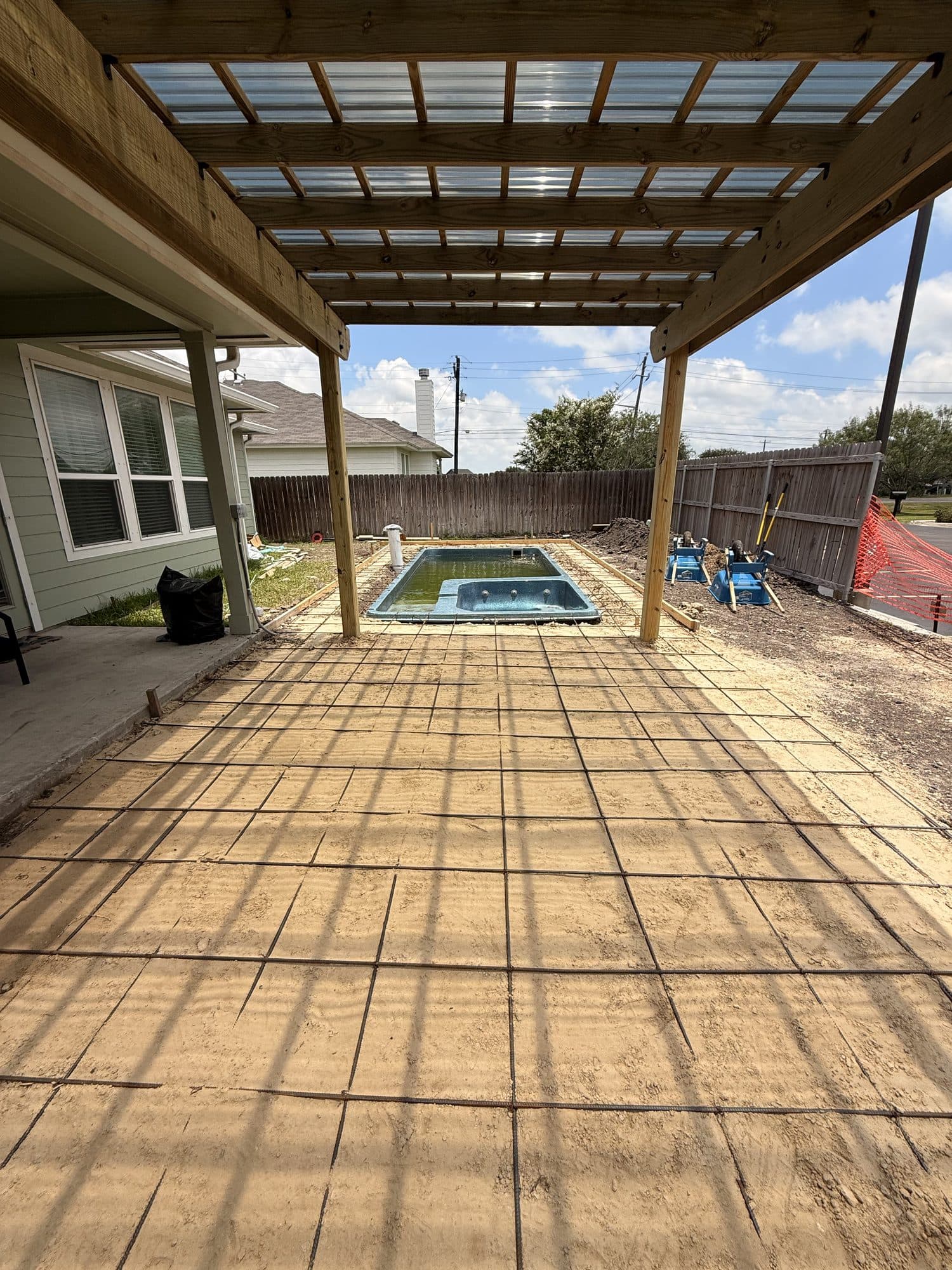 Pergola over a wood-plank stamped deck leading to a small pool
