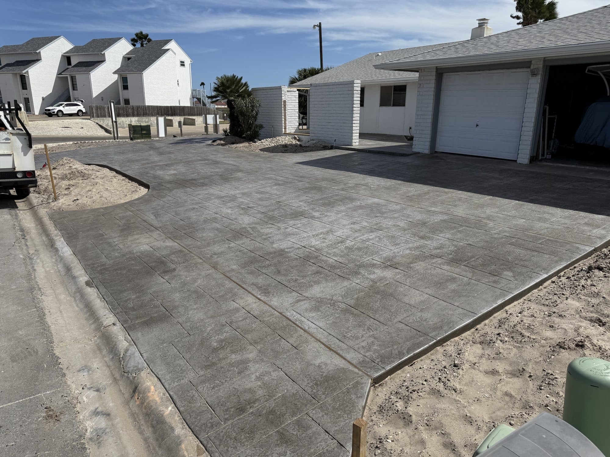 Stamped concrete driveway leading to a garage in a coastal neighborhood