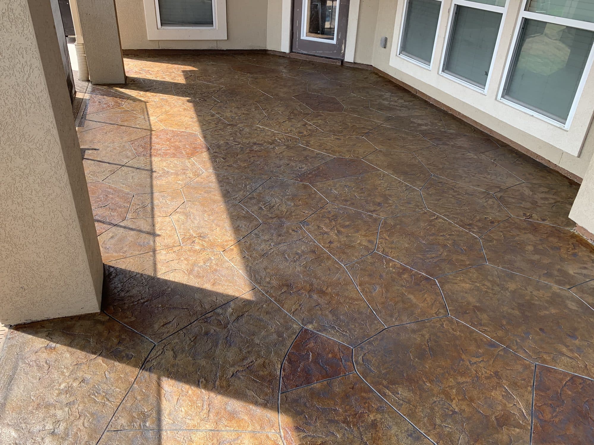 Rust-brown stamped flagstone patio running along a stucco home