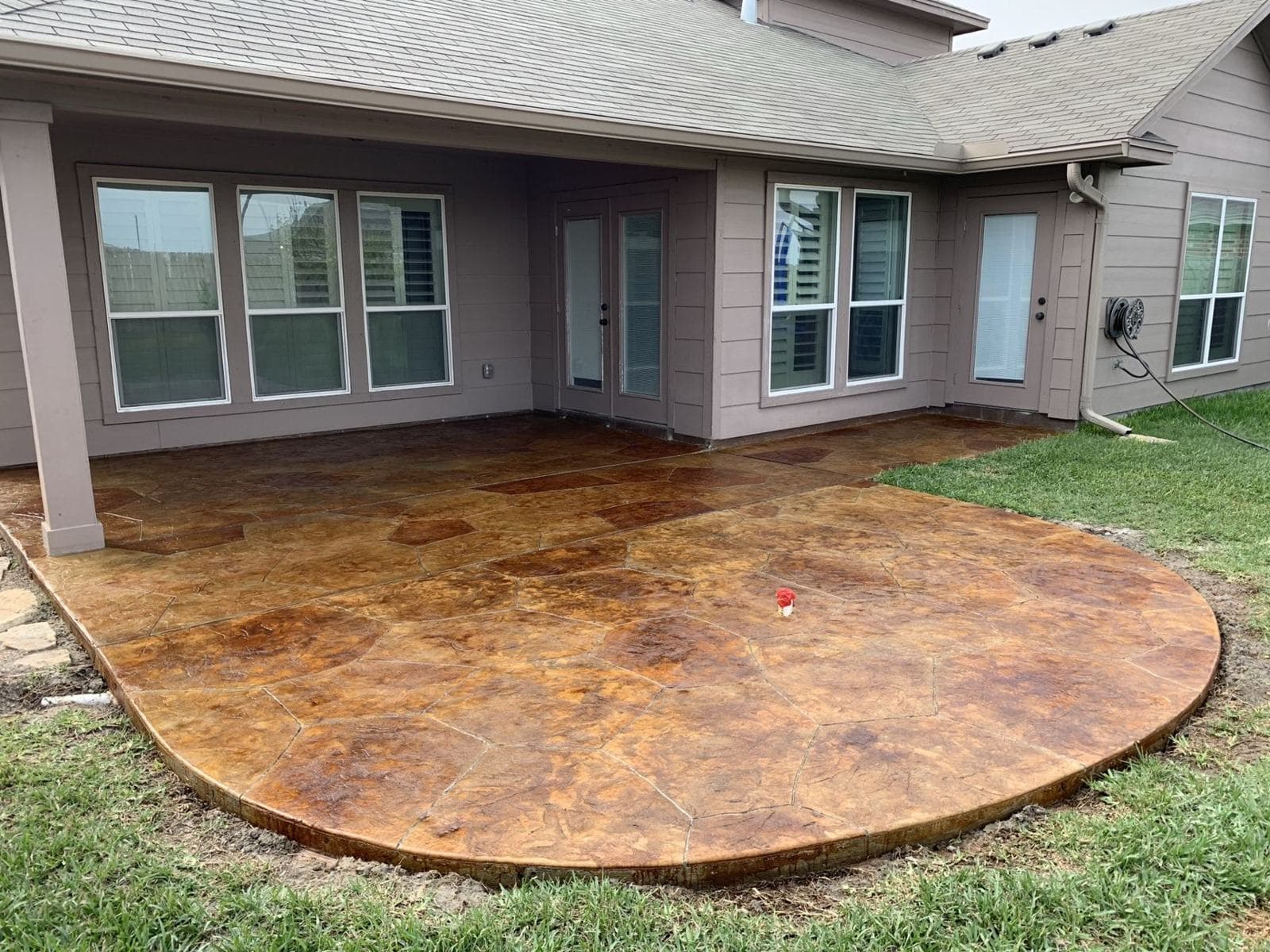 Round acid-stained concrete patio behind a home