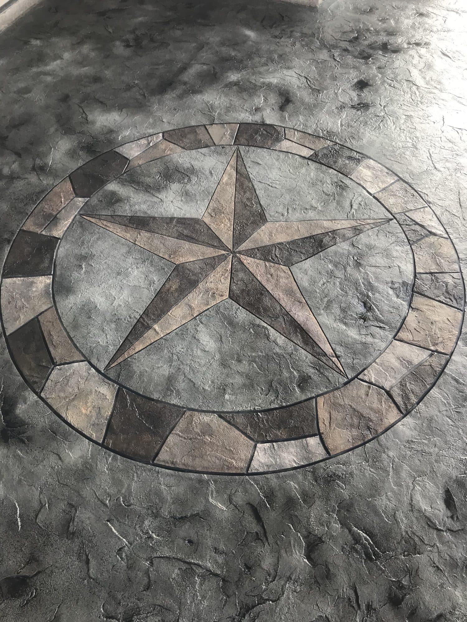 Close-up of a Texas star medallion stamped into slate-gray concrete