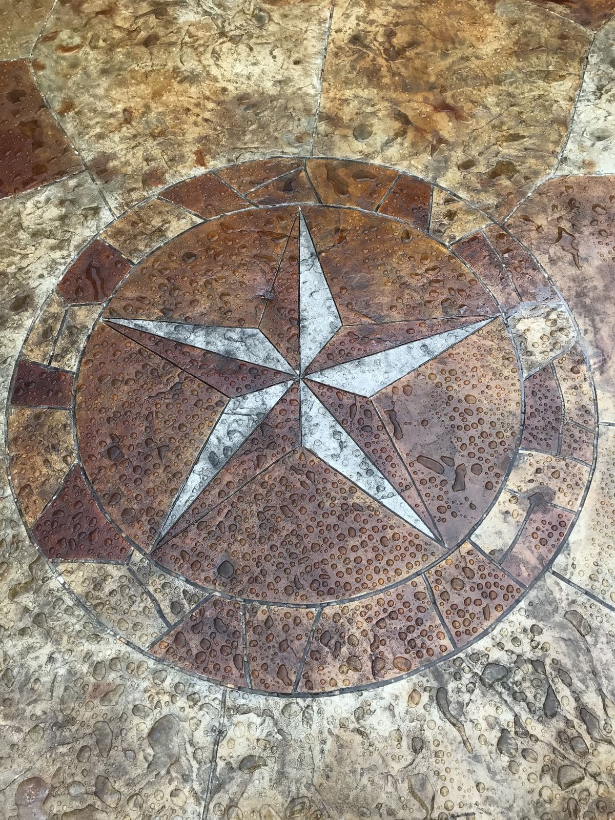 Close-up of a stamped concrete Texas star medallion in rust and gray tones